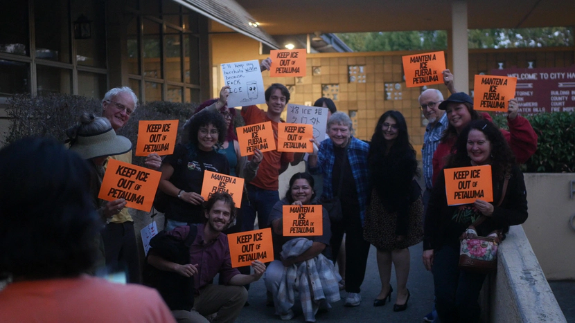Organizers with anti Ice signs help up to camera outside Petaluma City hall