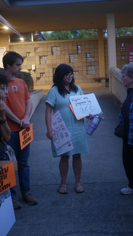 Woman holding anti Ice signs in various languages
